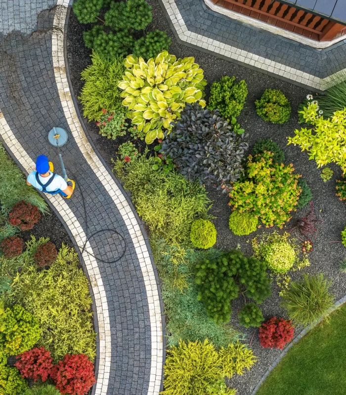 A top view of a man cleaning the hardscape path of a garden